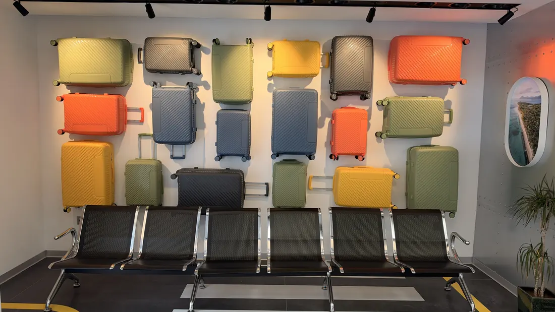 Pared de maletas de colores y sala de espera tipo aeropuerto