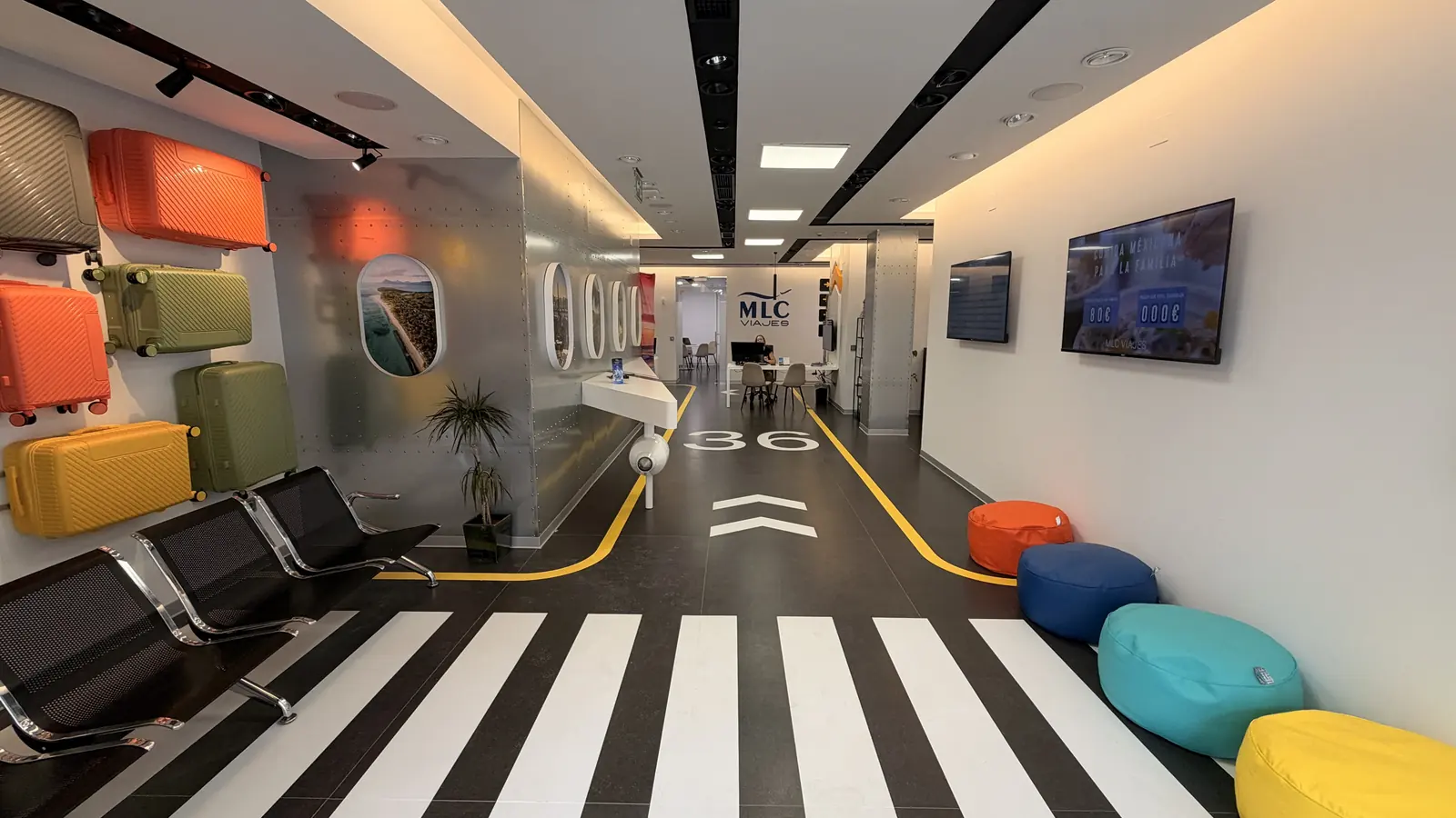 Interior de la agencia MLC Viajes: pasillo con pista de aeropuerto pintada en el suelo